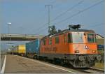 Die orange Re 4/4 II 11320  Interregio Cargo  mit einem Postzug in Chavornay.
